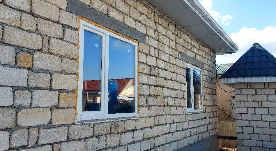 Два окна ПВХ разного размера в фасаде частного дома из ракушечника в Атырау